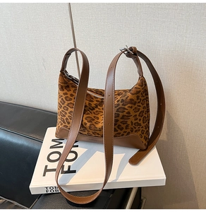 Close-up of leopard print shoulder bag with brown leather strap on a Tom Ford book