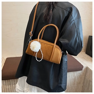 Brown suede bowling bag with faux pearl and pompom charm shown on a female model
