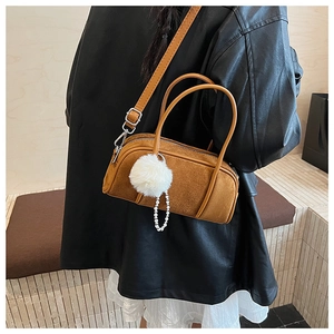 Brown retro cylinder crossbody bag with fuzzy pompom and pearl charms on model back