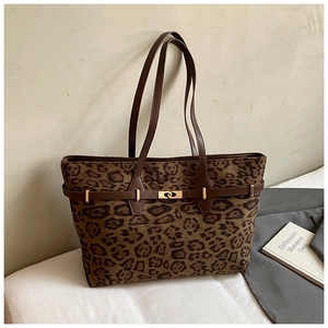 Macro detail of leopard print tote bag featuring golden twist lock and brown leather handle