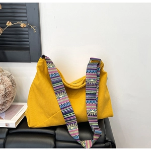 Detail of yellow corduroy tote bag featuring an ethnic style woven wide shoulder strap