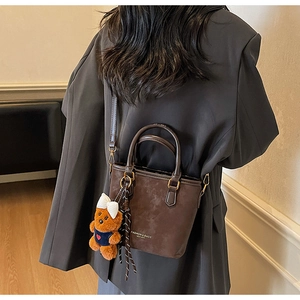 Detail of vintage brown suede crossbody bucket bag with cute plush bear charm