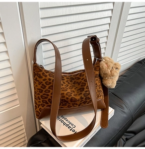 Detailed close-up of leopard print shoulder bag with brown leather strap and bear charm