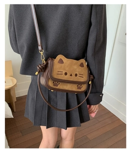 Detail of cute cat shaped crossbody bag showing side knot and gold metal hardware