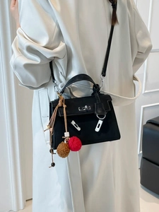 Classic black leather Kelly style crossbody bag with plush charms and silver lock