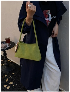 Street style shot of a green suede underarm bag with decorative colorful beads