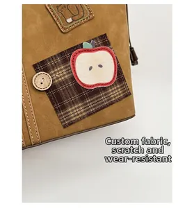 Detailed shot of brown suede tote bag featuring apple patch and wooden button detail