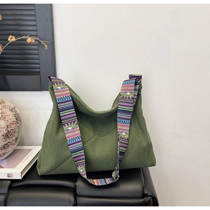 Close-up of green corduroy tote bag featuring a colorful ethnic-style woven shoulder strap