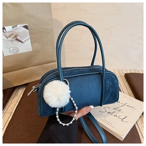Detail of navy blue suede Boston bag with fuzzy pom-pom and elegant pearl chain accessories