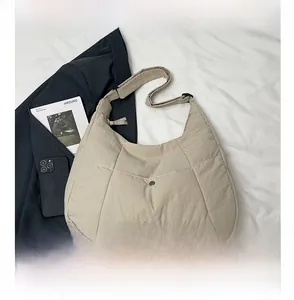 Détails d'un sac fourre-tout matelassé beige avec bandoulière réglable sur tissu blanc