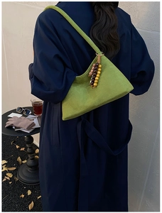 Green suede crossbody bag with vintage wooden beads shown in a lifestyle street setting