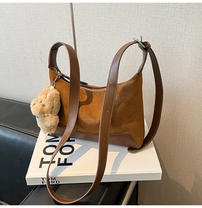 Detail view of retro leopard-style brown suede handbag with plush bear charm on books