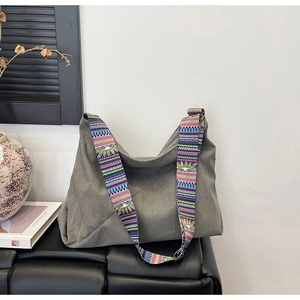 Grey corduroy hobo bag with ethnic style colorful wide strap in minimalist room setup