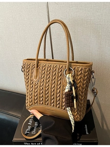 Brown woven bucket bag with V-shaped texture and decorative scarf on handle