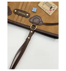 Close-up of brown suede tote bag featuring reinforced handle straps and Puppy embroidery