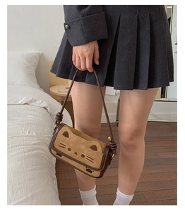 Detail of a vintage khaki suede crossbody bag featuring a cute cartoon cat face design