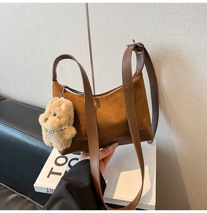 Detail of suede leopard style bag featuring a plush dog charm with pearl necklace