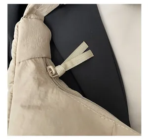 Détail de la fermeture éclair avec tirette en tissu sur le sac bandoulière beige en nylon