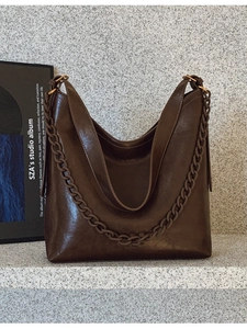 Minimalist large brown bucket bag in glossy oil wax leather with decorative chain strap