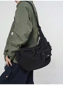Détails d'une sacoche noire en nylon avec tirettes texturées et poches multiples