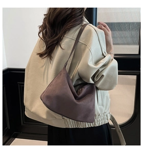 Detail of dark brown suede crescent shoulder bag showing its texture on model