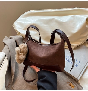 Detail of dark brown suede shoulder bag with smooth leather trim and plush pearl charm
