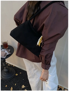 Minimalist black crossbody bag with decorative multi-colored wooden beads on the side