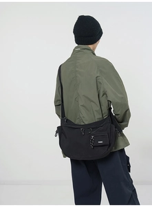 Détail d'un sac bandoulière en nylon noir forme demi-lune avec large sangle réglable