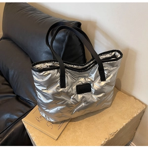 Détail du sac fourre-tout argenté matelassé avec poignées noires et étiquette mode