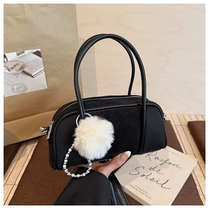 Detail of black suede bowling bag with white faux pearl chain and fluffy pom-pom charm