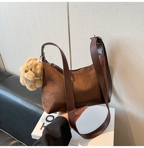 Detail of suede shoulder bag with brown leather trim and cute plush puppy charm