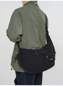 Détail d'un sac messager en nylon noir avec tirette tissée et bandoulière réglable