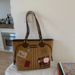Detail of vintage brown suede tote bag with puppy and apple embroidery patches