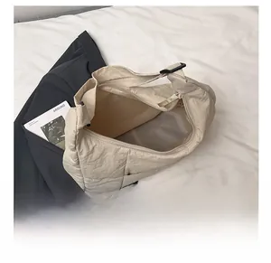 Vue intérieure du sac bandoulière en nylon beige avec compartiment spacieux et fermeture éclair