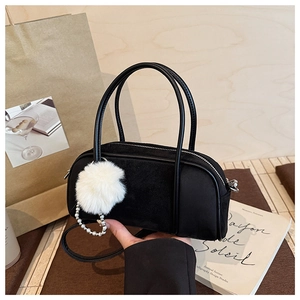 Detail of black bowling handbag featuring plush ball and pearl pendant accessories