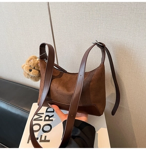 Detail of vintage brown suede hobo bag featuring smooth leather trim and cute bear charm