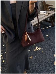 Detail of dark brown suede shoulder bag with bohemian wooden beaded charm and autumn vibe