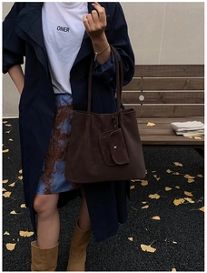 Detail of dark brown suede tote bag with small pouch in an autumn outdoor setting