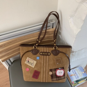 Macro view of brown suede tote bag with vintage embroidery and leather handles
