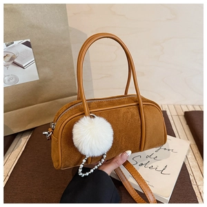 Close-up of brown suede bowling bag with white faux fur pompom and pearl chain detail