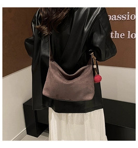 Detail of brown suede hobo bag with leather strap and decorative red plush charm