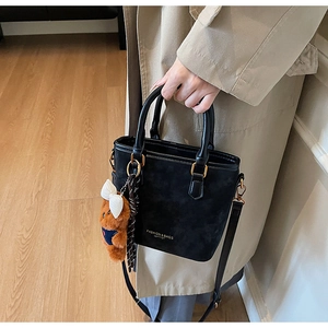 Detail view of black suede bucket bag with teddy bear charm and polka dot ribbon