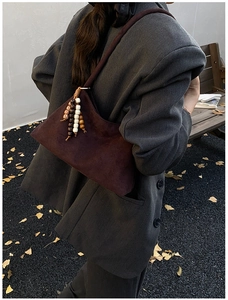 Detail of vintage brown suede shoulder bag with retro wooden beaded tassel decoration