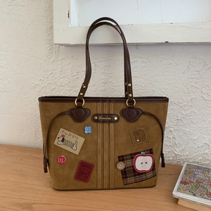 Detail view of brown faux leather tote with vintage puppy patches and embroidery