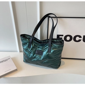 Détail du sac fourre-tout matelassé vert foncé avec tissu brillant et logo de mode