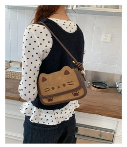 Detail of cute cat shaped brown crossbody bag with embroidery ears and paw prints