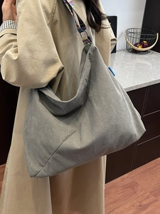 Grey corduroy tote bag with colorful geometric woven strap shown on a model