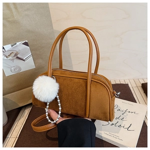 Detailed view of brown suede bowling bag with fluffy pompom and pearl chain accessory