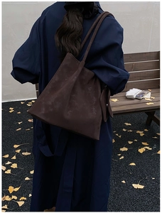 Deep brown oversized matte tote bag shown on model in a cozy autumn park setting