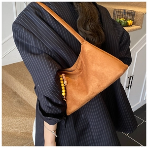 Brown suede underarm bag with decorative beads worn with a navy pinstripe suit